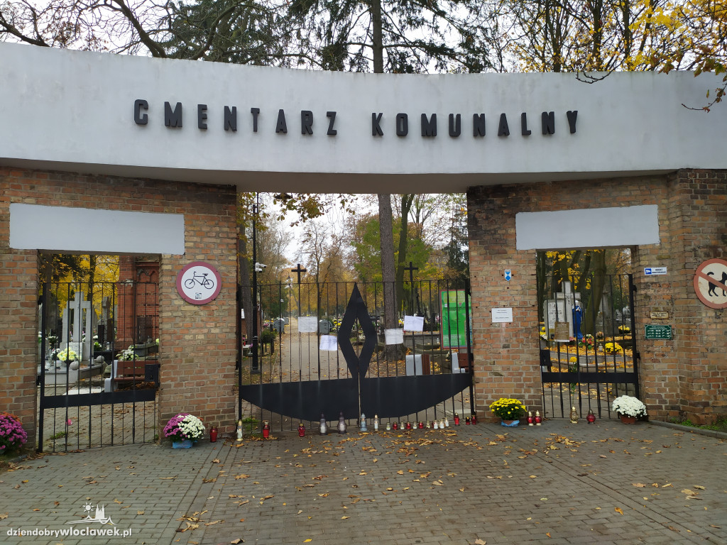 Znicze i kwiaty pod zamkniętymi bramami cmentarza