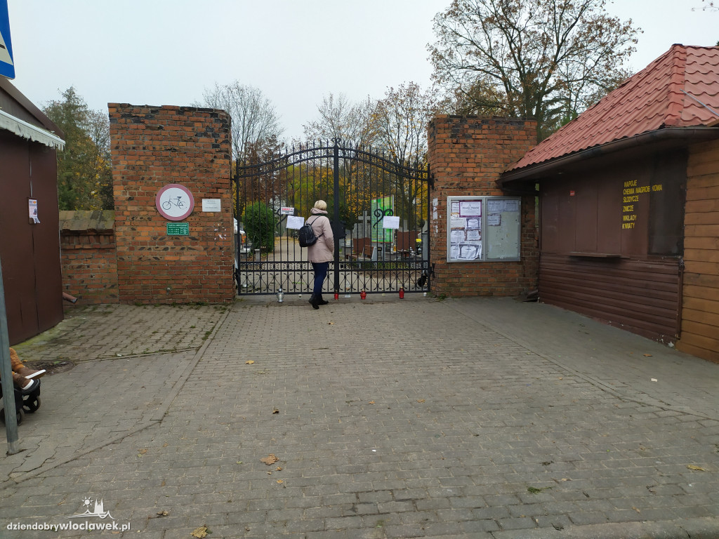 Znicze i kwiaty pod zamkniętymi bramami cmentarza