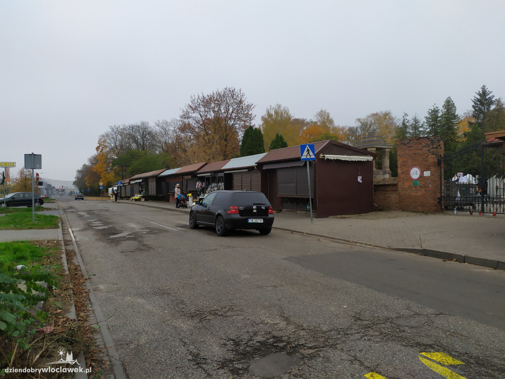 Znicze i kwiaty pod zamkniętymi bramami cmentarza